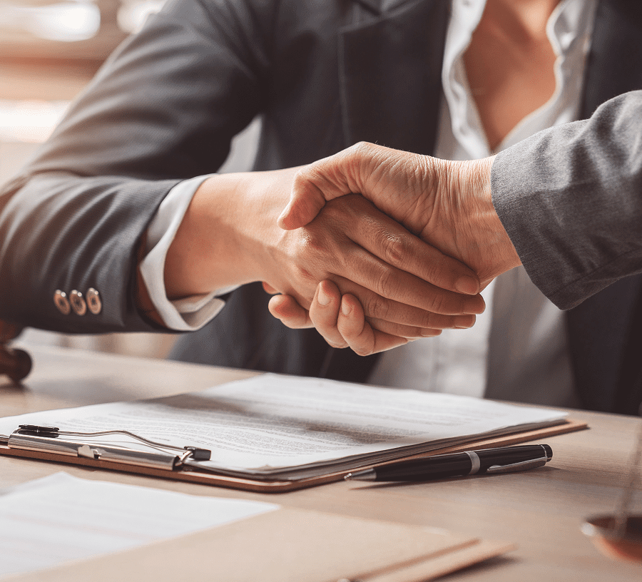 Business handshake over desk with documents